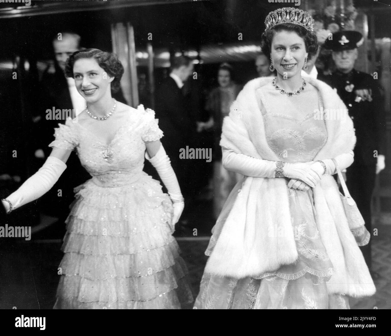 26 octobre 1953 - Londres, Angleterre, Royaume-Uni - LA REINE ELIZABETH II, à droite, avec sa sœur, LA PRINCESSE MARGARET, à gauche, et LE PRINCE PHILIP, vue partielle floue derrière la princesse, arrivent au théâtre Odeon, à Leicester Square pour assister à la représentation royale du film « Rob Roy » vêtu d'une tenue de soirée. (Image de crédit : © Keystone Press Agency/ZUMA Press Wire) Banque D'Images