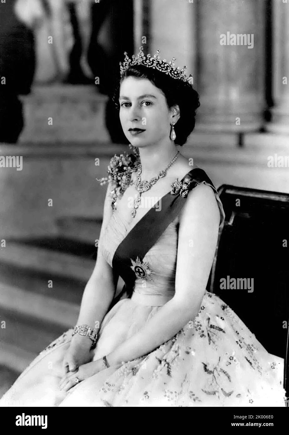 26 janvier 1954, Londres, Angleterre, Royaume-Uni : Nouveau Portrait de commandement royal de la reine Elizabeth II au palais de Buckingham. : H.M. la reine a posé pour ce nouveau portrait sur le petit escalier de la Grande entrée du palais de Buckingham. Elle porte une robe de soirée en tulle jaune ornée de jets de mimosa et de broderie de paaillette d'or - et le ruban bleu et l'étoile de la jarretière. Son collier est un cadeau de mariage du Nizam de Hyderabad - le Tiara est un cadeau de mariage de sa grand-mère. La broche d'arc - pendants d'oreilles, bracelet et montre de poignet en platine sont également fixés en diamants. Image Banque D'Images