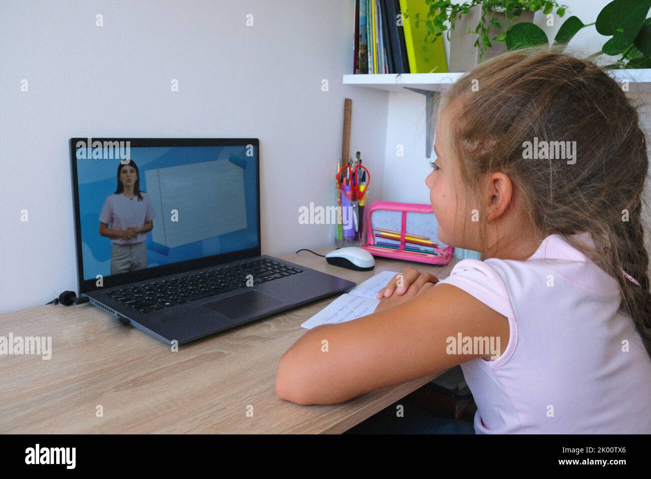 Une fille heureuse et souriante étudie en ligne. Concept d'enseignement à distance. Banque D'Images