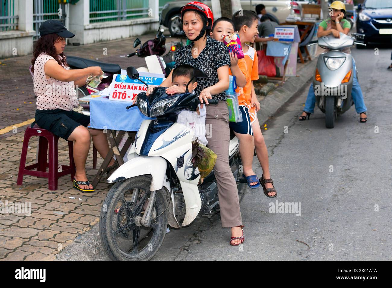 Mère vietnamienne et enfants sur moto acheter à la rue vendeur, Hai Phong, Vietnam Banque D'Images