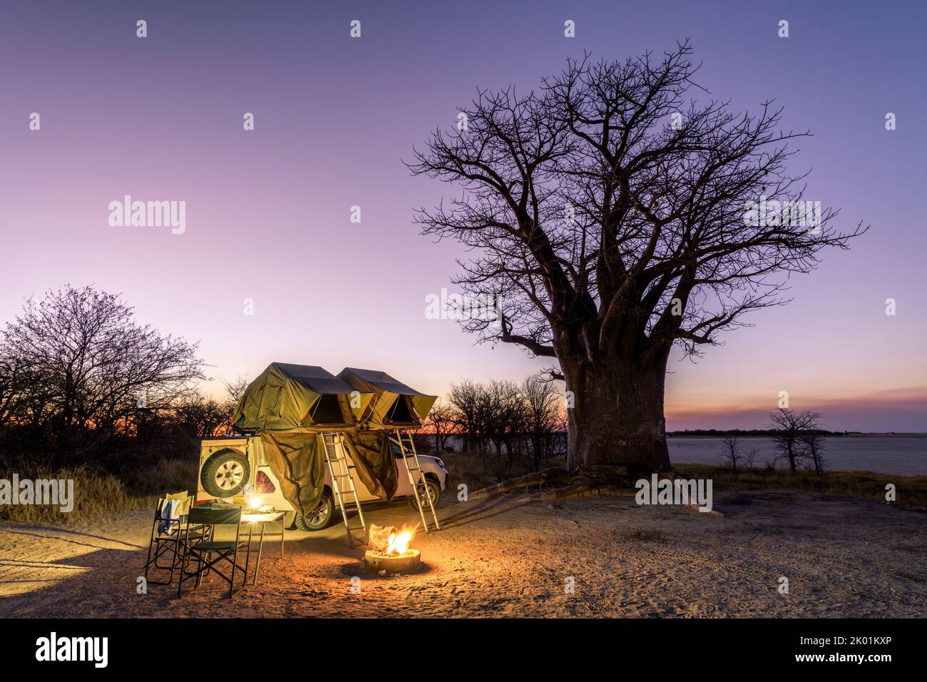 Afrique - Camping dans le désert avec feu et soleil en face d'un arbre Baobab, Nxai Pan, Botswana Banque D'Images