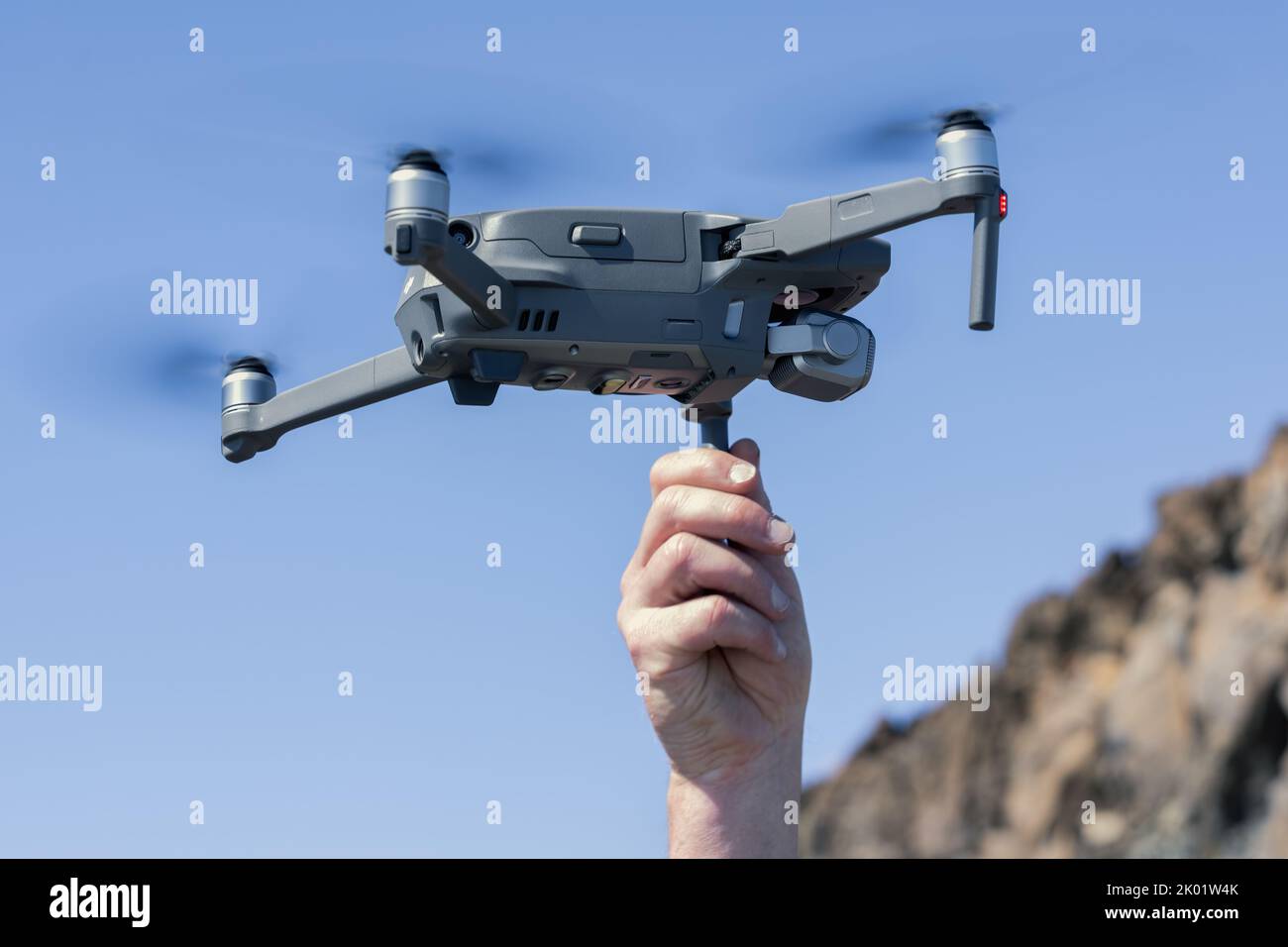 Homme main lançant un drone contre le ciel bleu Banque D'Images