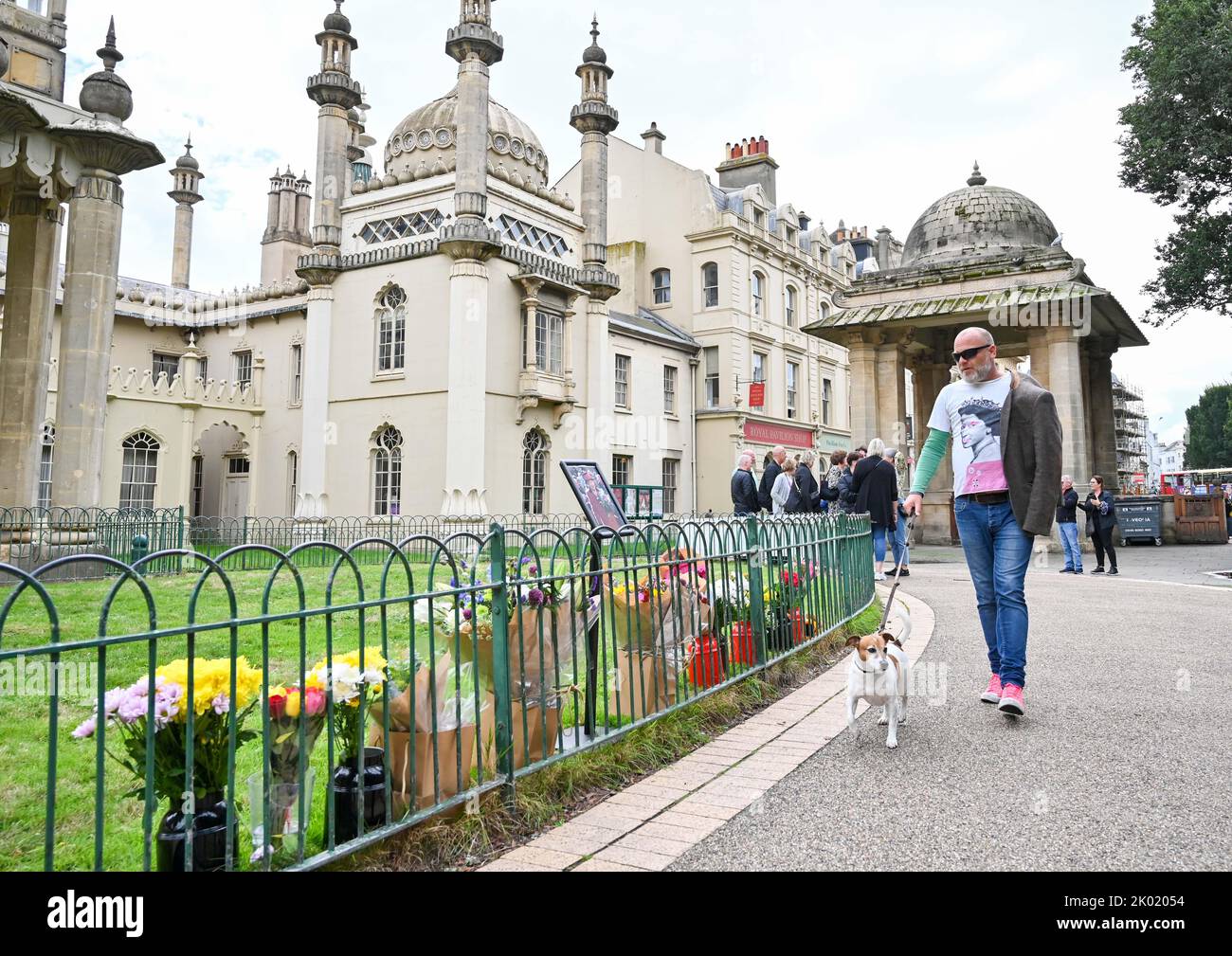 Brighton UK 9th septembre 2022 - Un membre du public portant un t-shirt Queen passe par des hommages floraux à la Reine devant le Pavillon Royal de Brighton aujourd'hui après sa mort à l'âge de 96 ans a été annoncé hier . Elizabeth II a régné comme monarque britannique pendant 70 ans : crédit Simon Dack / Alamy Live News Banque D'Images