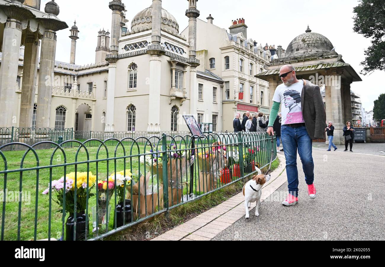 Brighton UK 9th septembre 2022 - Un membre du public portant un t-shirt Queen passe par des hommages floraux à la Reine devant le Pavillon Royal de Brighton aujourd'hui après sa mort à l'âge de 96 ans a été annoncé hier . Elizabeth II a régné comme monarque britannique pendant 70 ans : crédit Simon Dack / Alamy Live News Banque D'Images