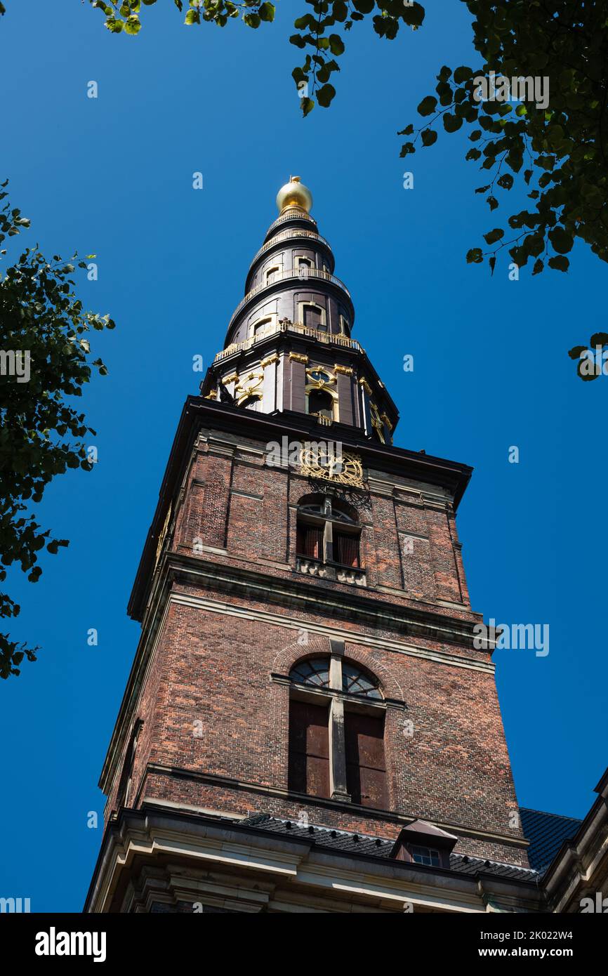 La tour de l'Église de notre Sauveur à Copenhague, Danemark contre le ciel bleu en été encadré par des branches d'arbres Banque D'Images