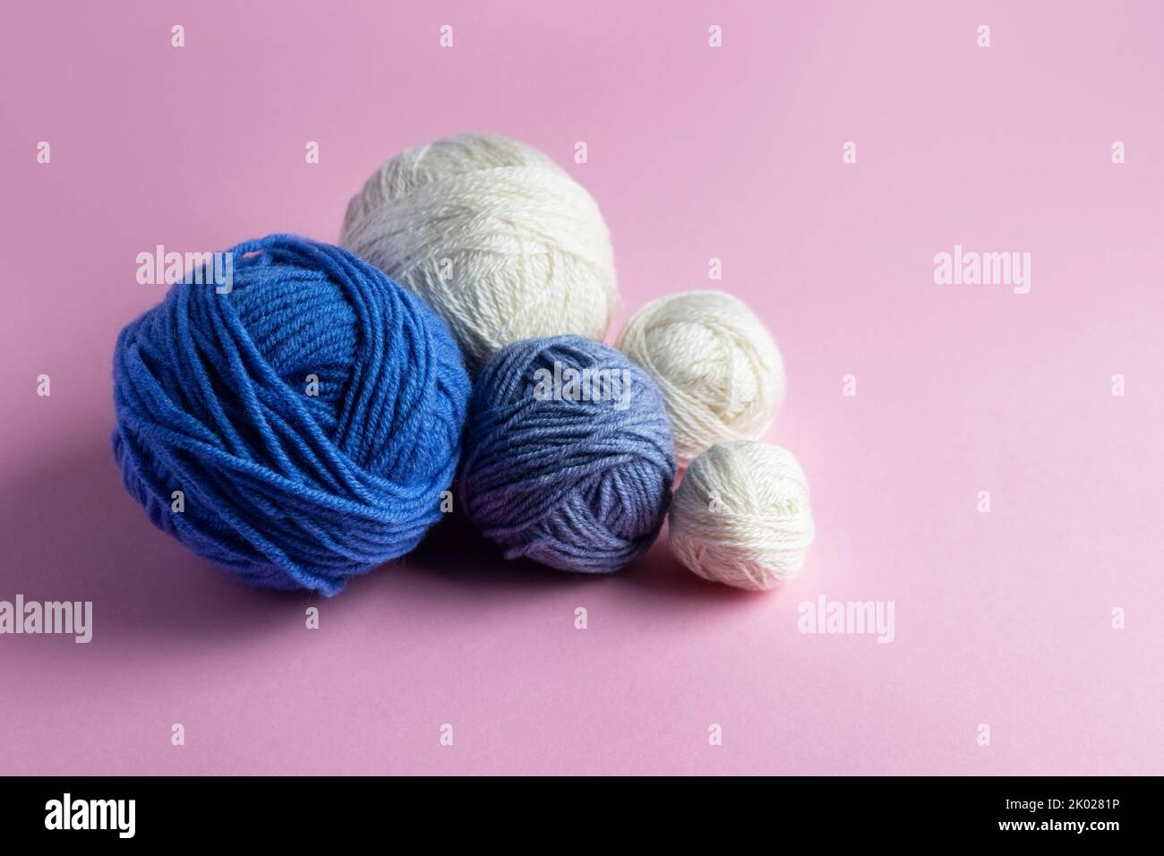 Laine tricotée bleue et blanche sur fond rose pour tricoter des vêtements chauds, des passe-temps Banque D'Images