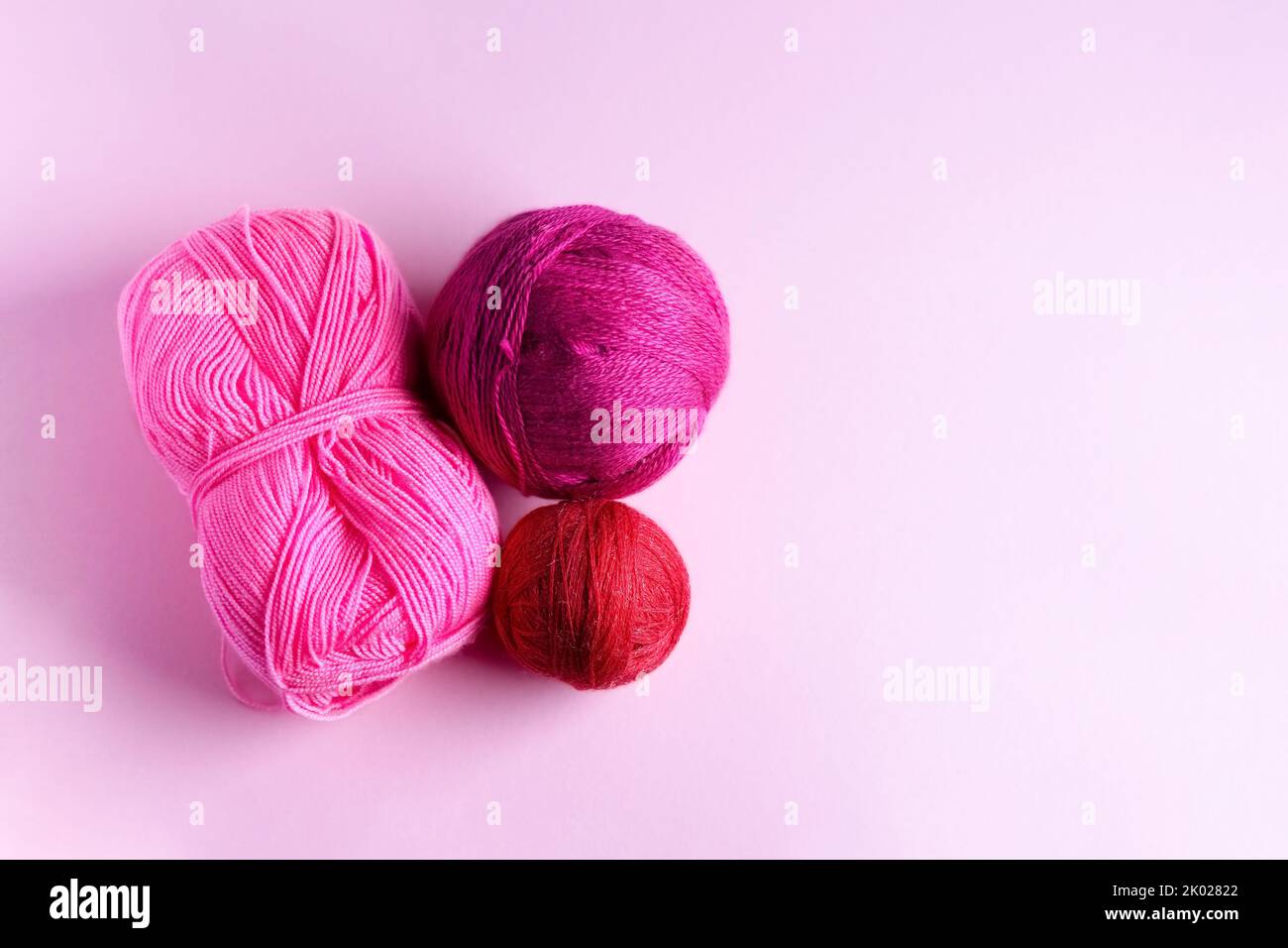 Laine tricotée rose rouge et violet sur fond lilas, passe-temps Banque D'Images