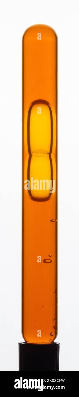Lécithine de tournesol liquide visqueuse jaune avec bulles dans un tube à essai transparent sur fond blanc Banque D'Images