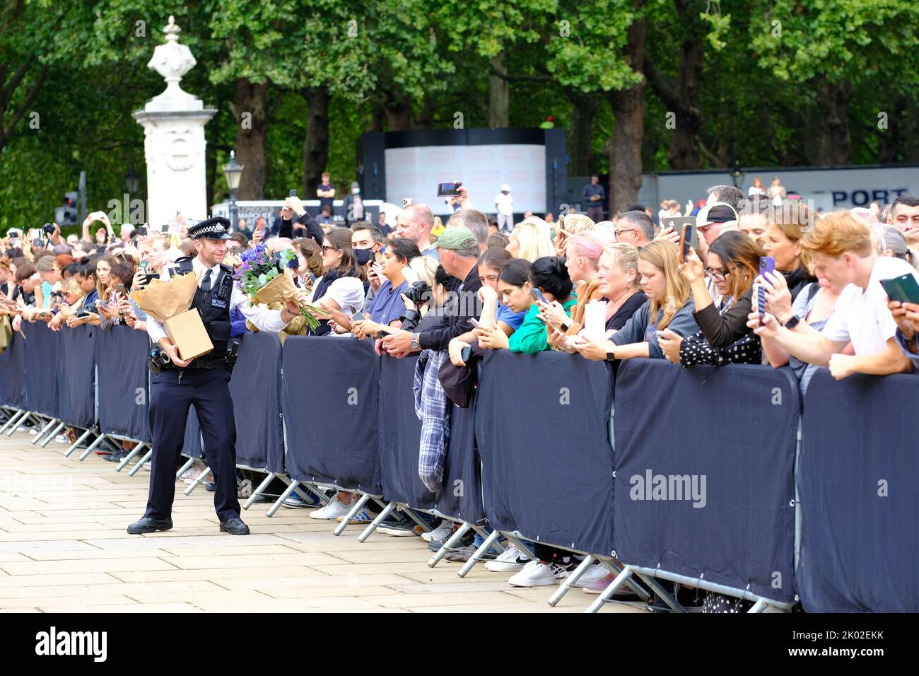 Buckingham Palace, Londres, Royaume-Uni – vendredi 9th septembre 2022 – Un policier reçoit des fleurs transmises par la grande foule devant Buckingham Palace alors que le public pleure la mort de la reine Elizabeth II hier. Photo Steven May / Alamy Live News Banque D'Images