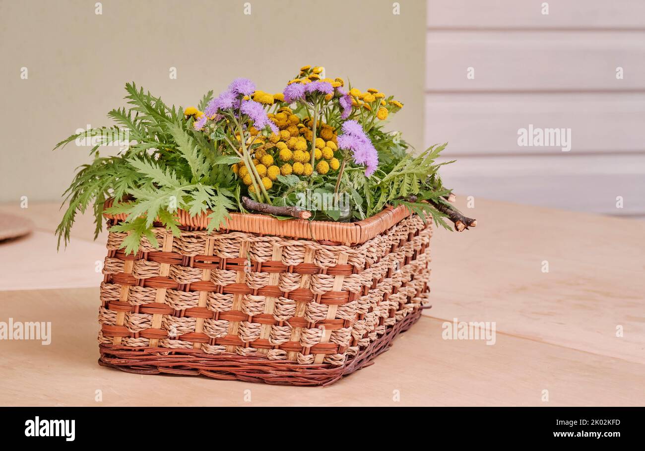 Bouquet de fleurs et de plantes sauvages dans un panier rectangulaire en osier. Banque D'Images