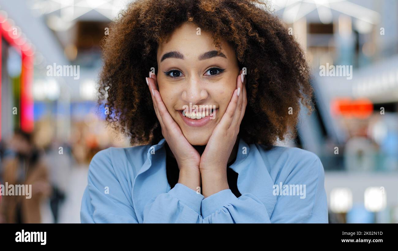 Portrait féminin à l'intérieur gros plan bonheur afro-américain mauriquement femme fille tenant le visage avec les mains de surprise gagnant joie stupéfait des nouvelles inattendues Banque D'Images