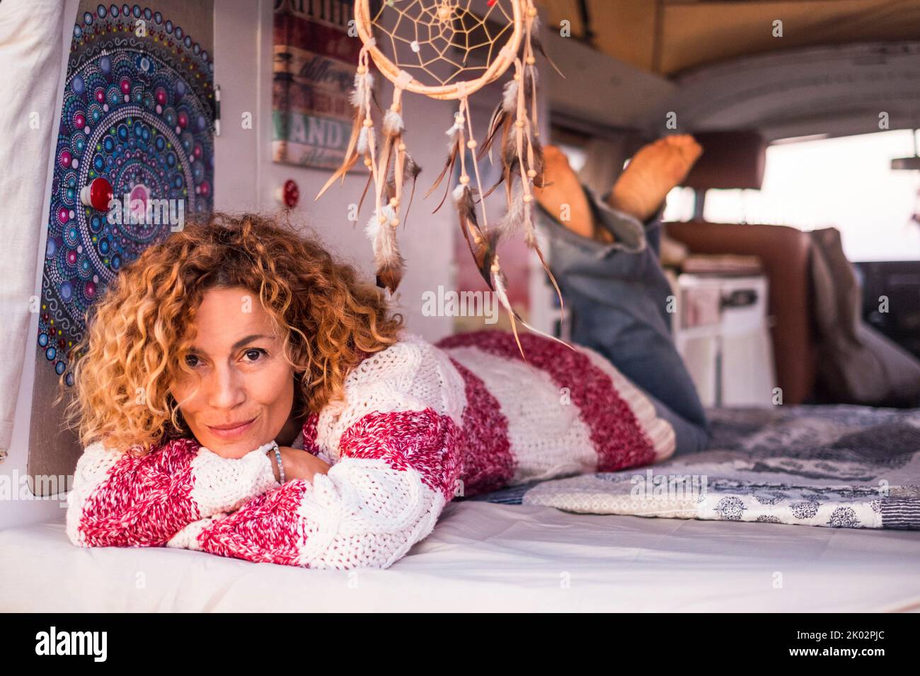 Portrait attrayant et gai d'une femme d'âge moyen qui se pose et se détend dans une camionnette de camping classique. Vanlife et les gens qui jouissent de la liberté. Style de vie de voyage. Sereine femme appréciant petite maison de camping Banque D'Images