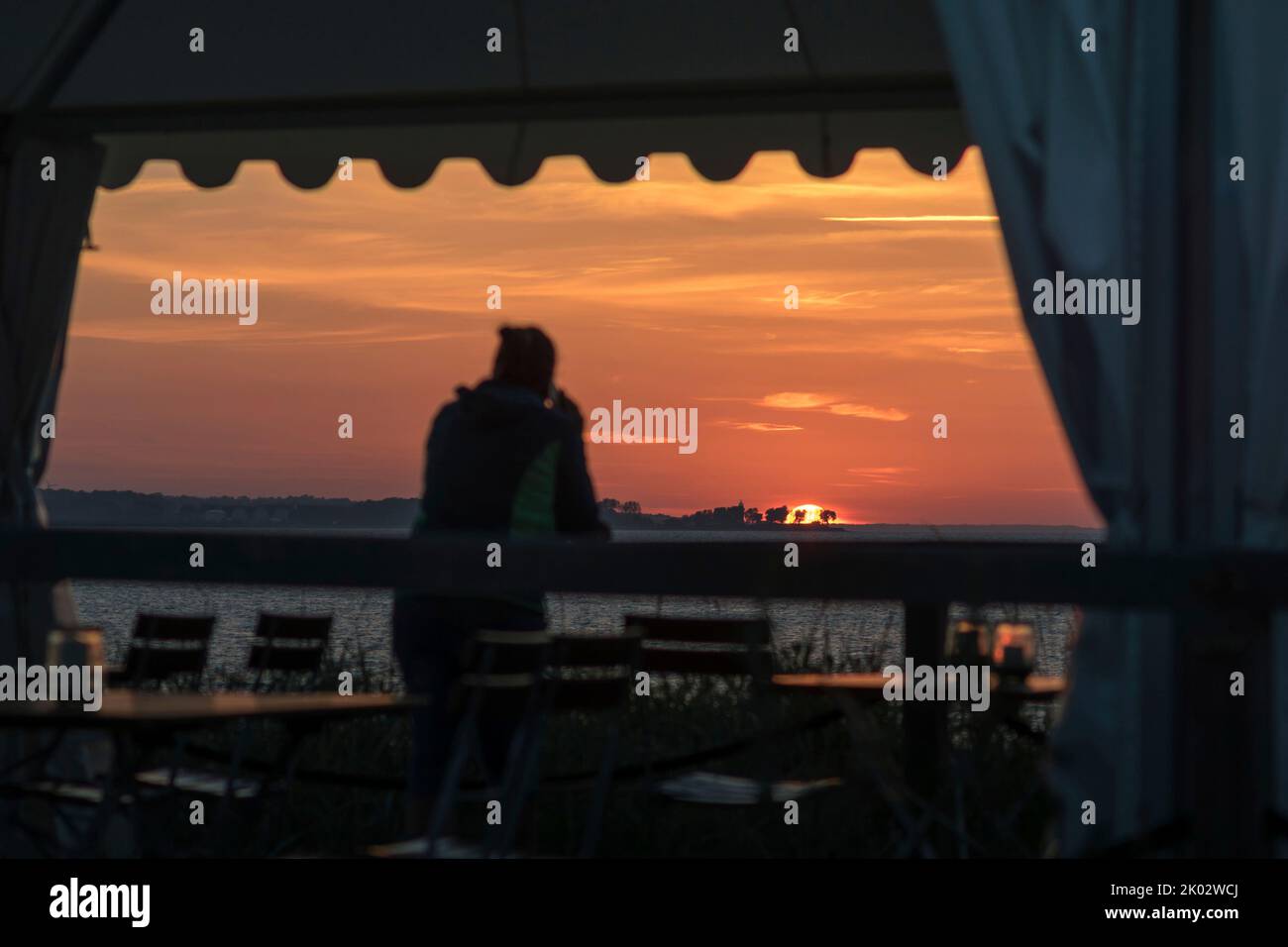 Personne sur la terrasse du restaurant donne sur le coucher de soleil sur la mer. Banque D'Images