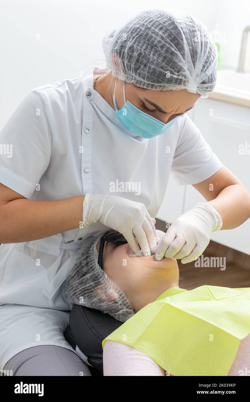 Dentiste installant un rétracteur de joue de patient dans un cabinet de dentiste Banque D'Images Dentiste installant un rétracteur de joue de patient dans un cabinet de dentiste Banque D'Images