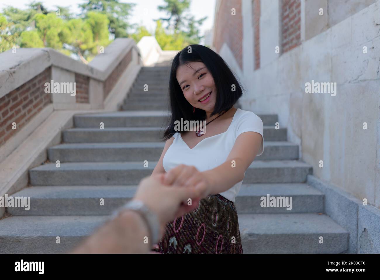 Jeune heureuse et belle asiatique japonaise femme posant à l'extérieur heureux et gai dans la ville enceinte montrant son ventre fier sourire pendant la grossesse an Banque D'Images
