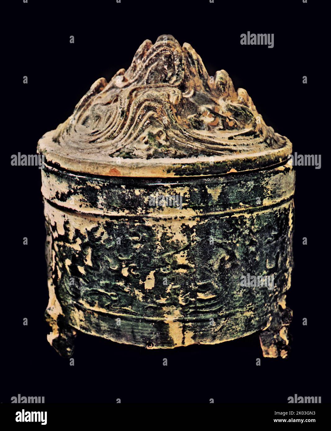 Ce bocal cylindrique a des motifs de montagne et de vague empilés haut sur la couverture, son fond se tient sur trois pieds en forme d'animal. Les patrons ressemblent à ceux que l'on trouve communément sur les bronzes et les reliefs d'argile des Han. Il a été tiré à une température élevée. Banque D'Images