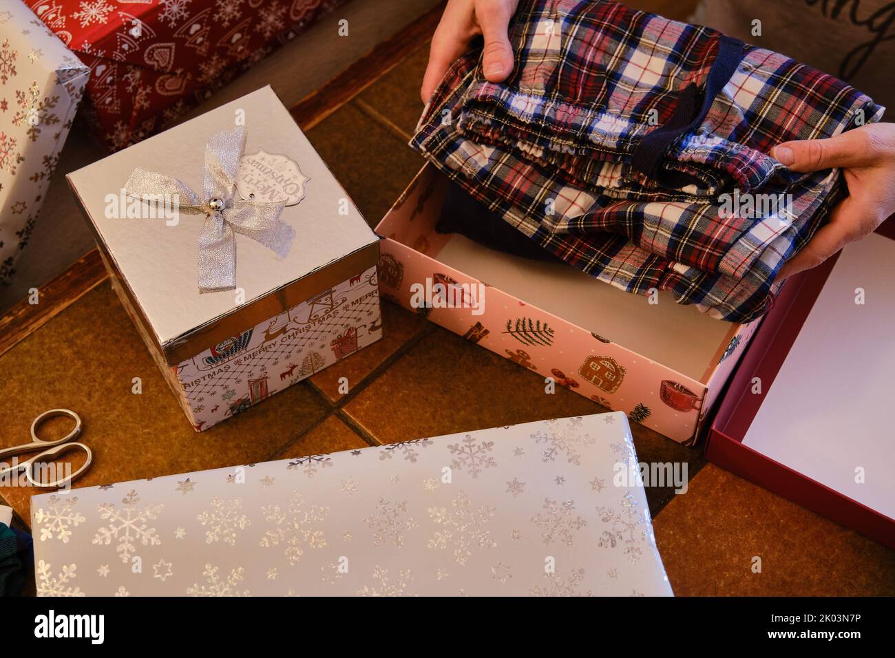 Gros plan sur les mains d'une femme qui enveloppent les cadeaux de Noël Banque D'Images