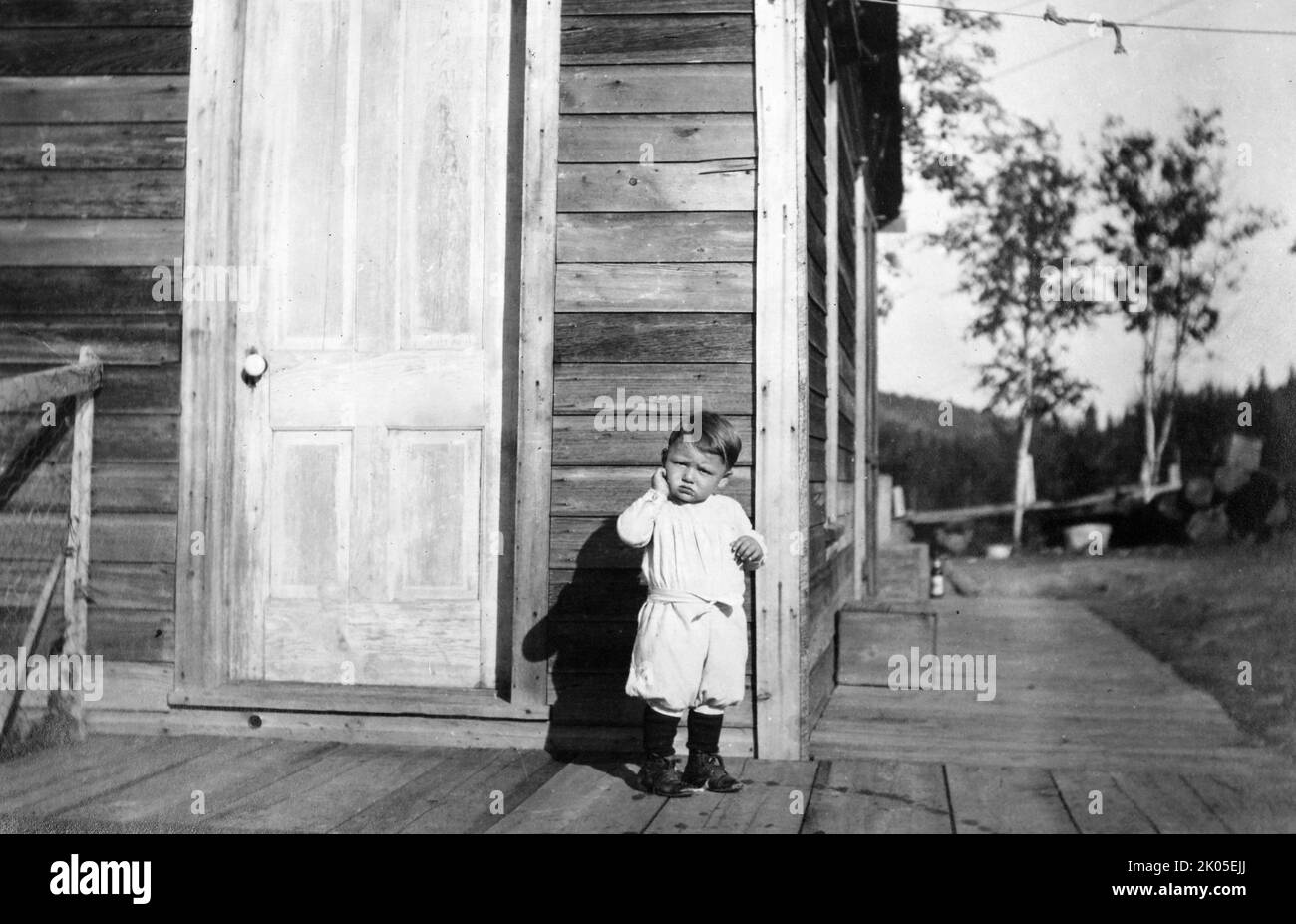 Un jeune garçon se tient sur le porche de sa ferme Colorado, ca. 1910. Banque D'Images