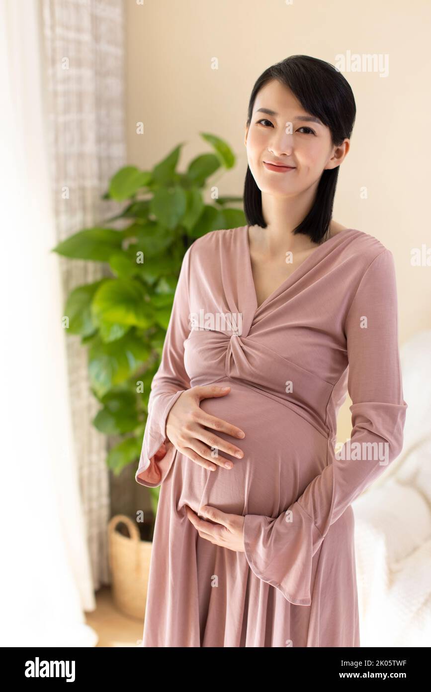 Chinois joyeuse femme enceinte détente à la maison Banque D'Images