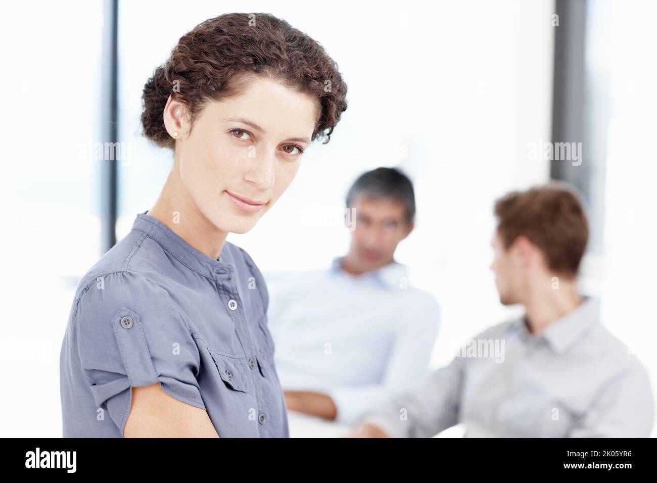 Diriger son équipe vers le haut. Portrait d'une employée de bureau confiante avec des collègues assis derrière elle. Banque D'Images