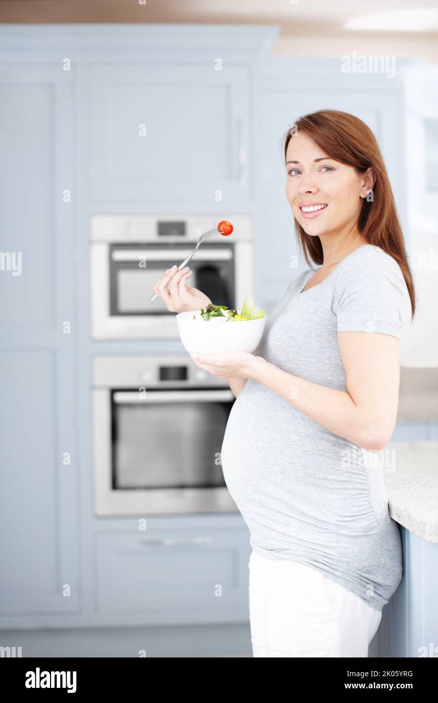 Un repas sain pour deux. Une femme enceinte qui mange une salade saine dans la cuisine. Banque D'Images
