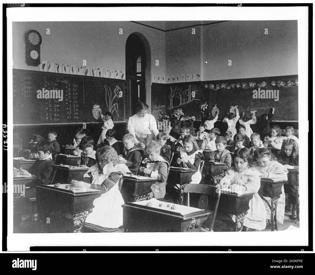 Les enfants qui modélisent de l'argile aux bureaux et qui dessient sur un tableau noir dans une salle de classe de Washington, D.C., (1899?). Banque D'Images