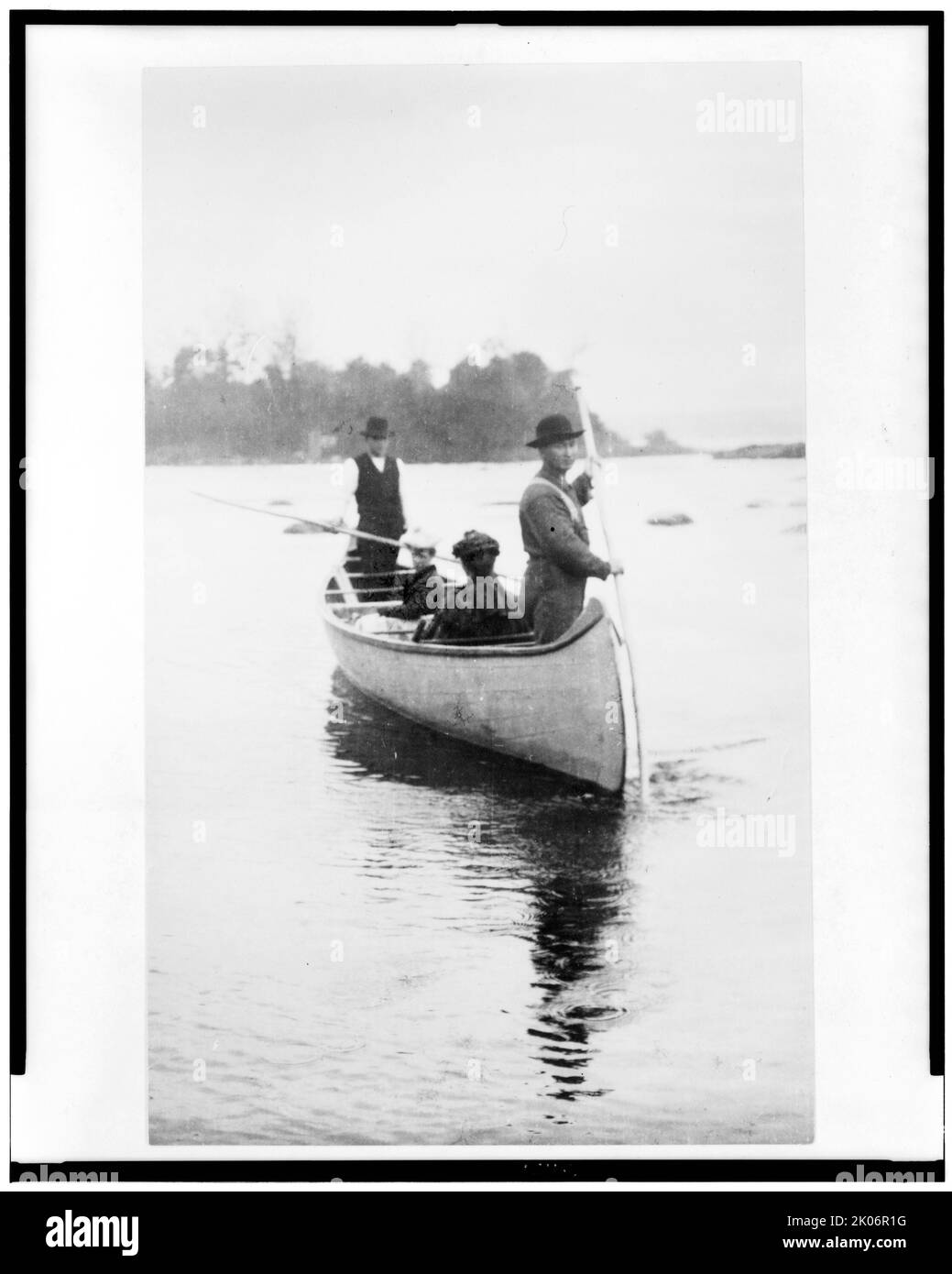 Deux guides indiens(?) debout, et deux femmes assises, en canot, dans la région de Sault Sainte Marie, au Michigan, en 1903. Banque D'Images