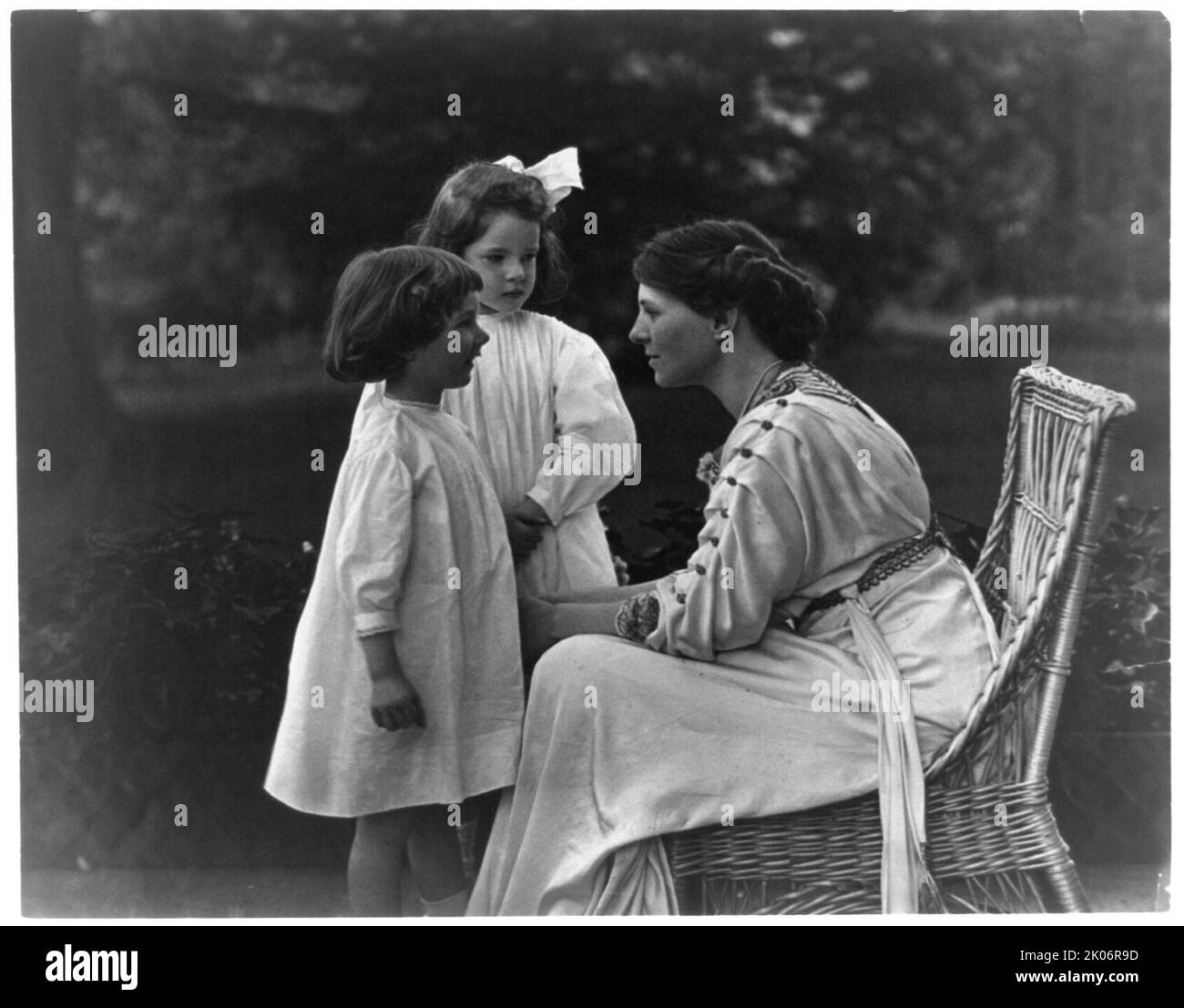 Mme Frank Vanderlip s'est assise sur le porche, avec deux enfants, pas après 1913. [Narcissa Cox Vanderlip était suffragiste, présidente de l'infirmerie de New York pour les femmes et les enfants, cofondatrice de la New York State League of Women Volisters, et mère de six enfants. Elle et son mari Frank A. Vanderlip ont fondé l'école Scarborough, la première école Montessori aux États-Unis]. Banque D'Images