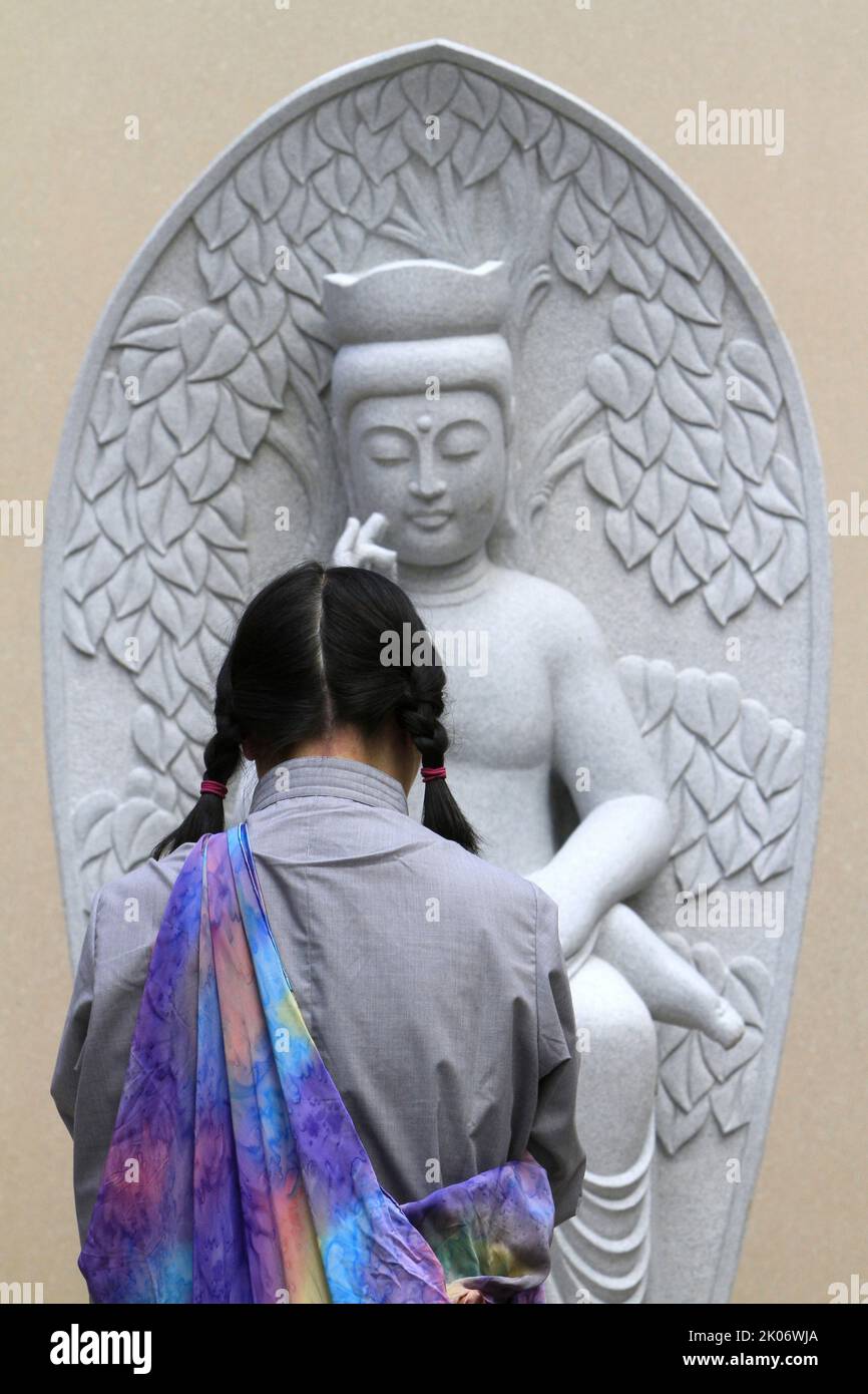 Jeune femme ayant une statue de Bouddha. FO Guang Shan temple le plus grand temple bouddhiste d'Europe. Bussy-Saint-Georges. Seine-et-Marne. Fran Banque D'Images