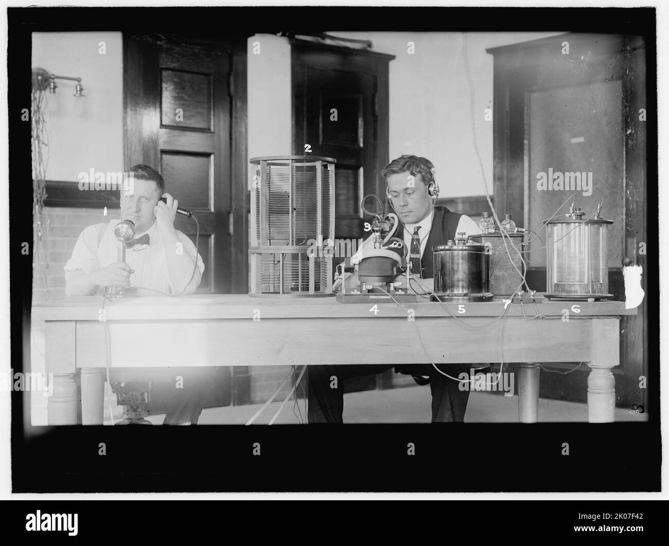 Laboratoire, entre 1909 et 1914. ÉTATS-UNIS. Homme à gauche utilisant un téléphone, homme à droite portant un casque et faisant fonctionner un appareil scientifique. Banque D'Images