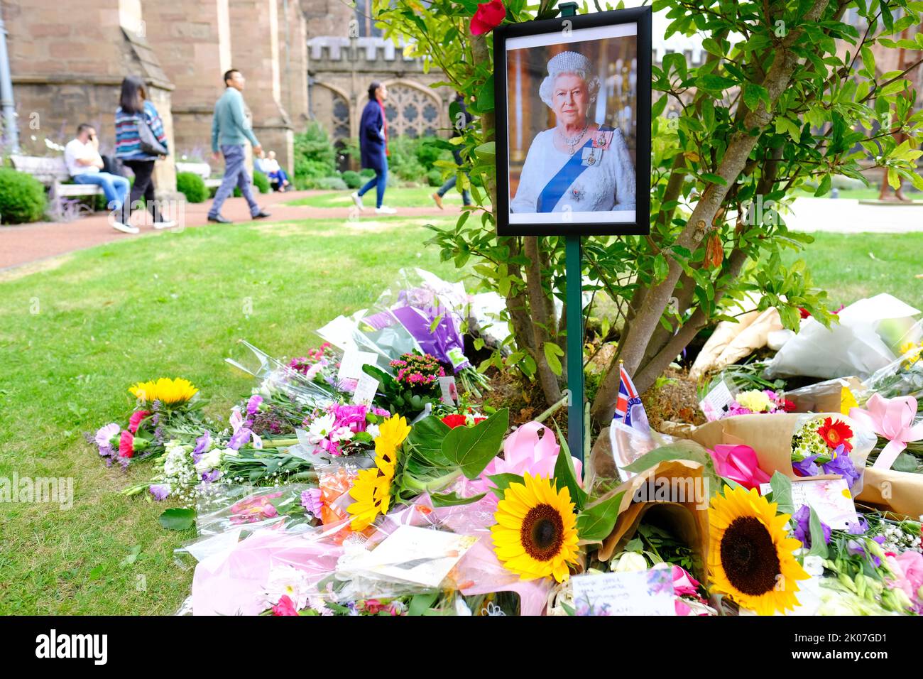 Hereford, Herefordshire, Royaume-Uni - Samedi 10th septembre 2022 - des bouquets de fleurs se trouvent à côté d'un portrait de la reine Elizabeth II dans les jardins de la cathédrale d'Hereford alors que la Grande-Bretagne pleure la mort du monarque. Photo Steven May / Alamy Live News Banque D'Images