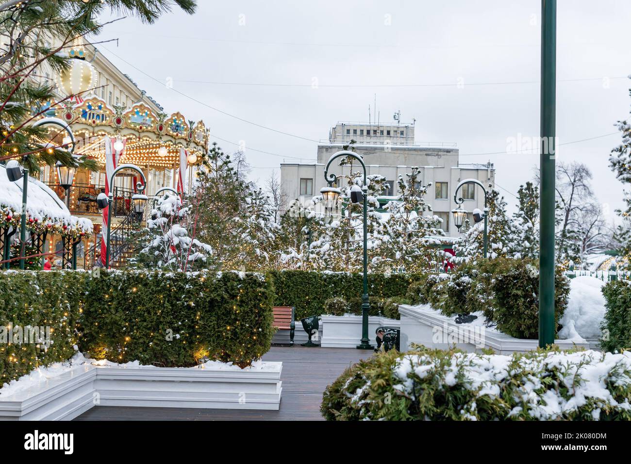 Carrousel festif à la place d'hiver parmi les trees de noël. Paysage urbain magique et enneigé. Banque D'Images
