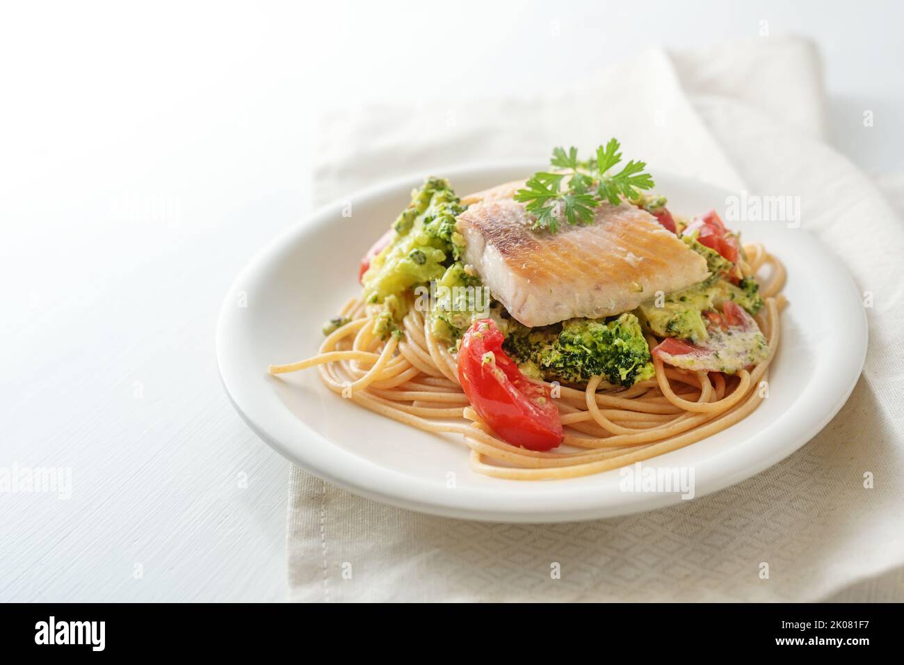 Filet de saumon sauvage sur spaghetti de grains entiers avec garniture de brocoli, tomates et persil, repas de fruits de mer sains sur une assiette blanche, copier le rythme, sélection de FO Banque D'Images
