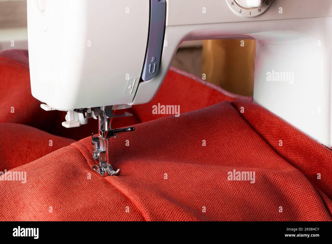Machine à coudre moderne en tissu rouge. Processus de couture. Copier l'espace. Banque D'Images