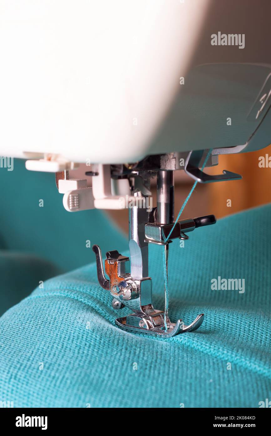 Machine à coudre moderne en tissu turquoise. Processus de couture. Banque D'Images