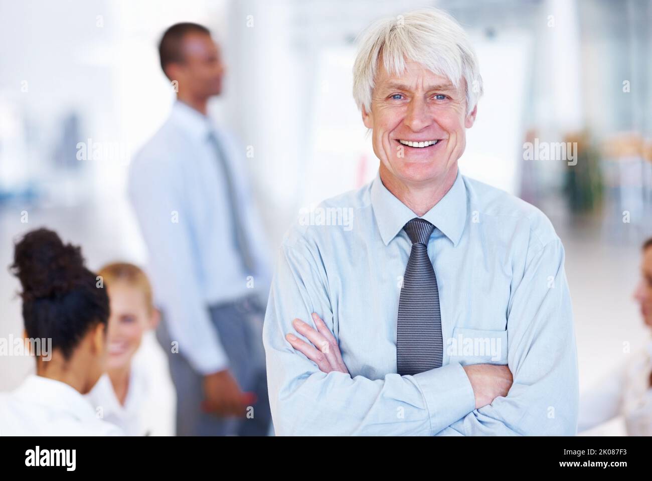 Homme d'affaires senior souriant en toute confiance. Portrait d'un dirigeant homme expérimenté confiant souriant avec des hommes d'affaires au bureau. Banque D'Images
