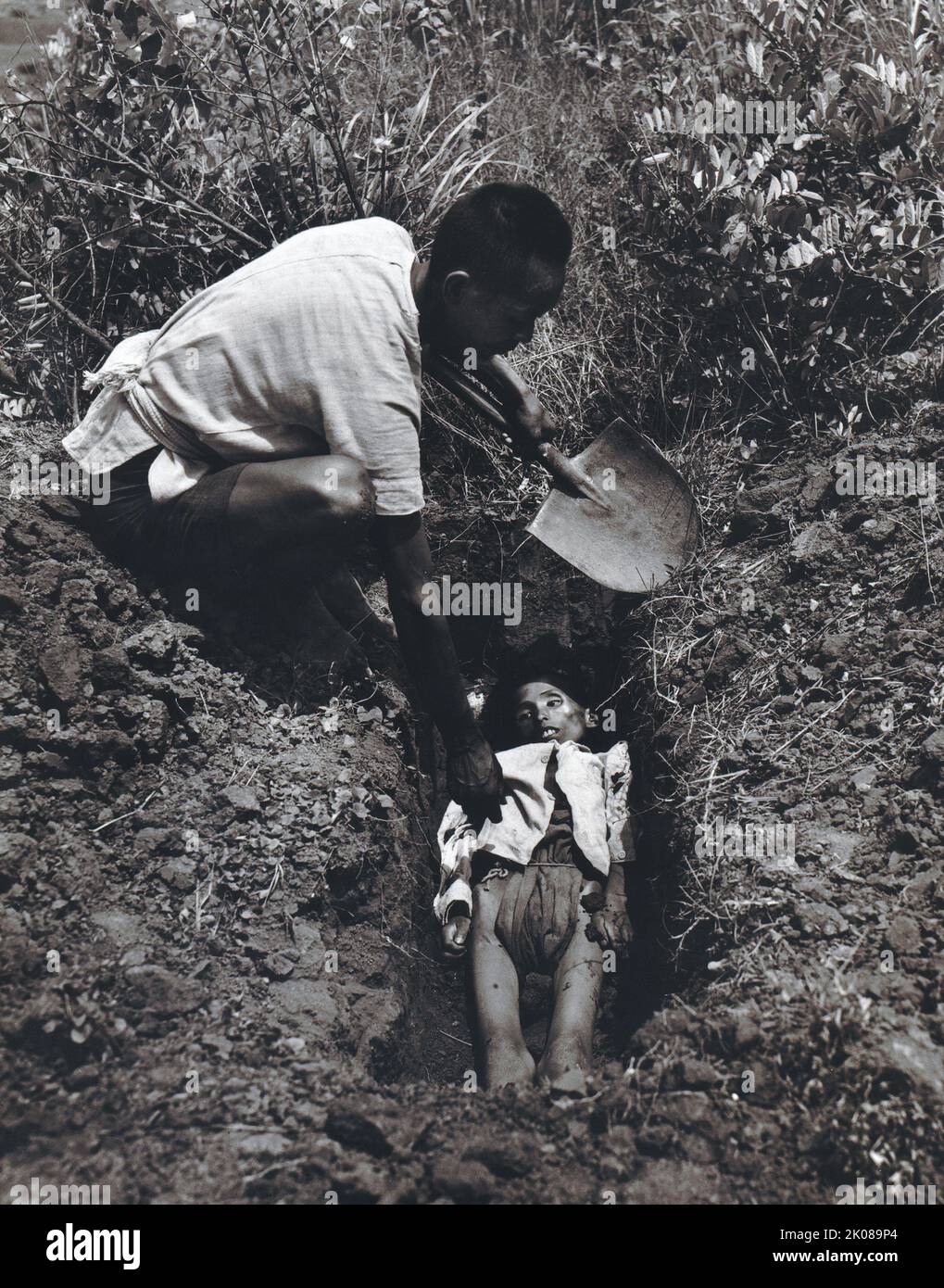 Homme enterrant un enfant dans une zone rurale de la province de Kiangsu ou de la province du Yunnan en Chine, 1946 Banque D'Images