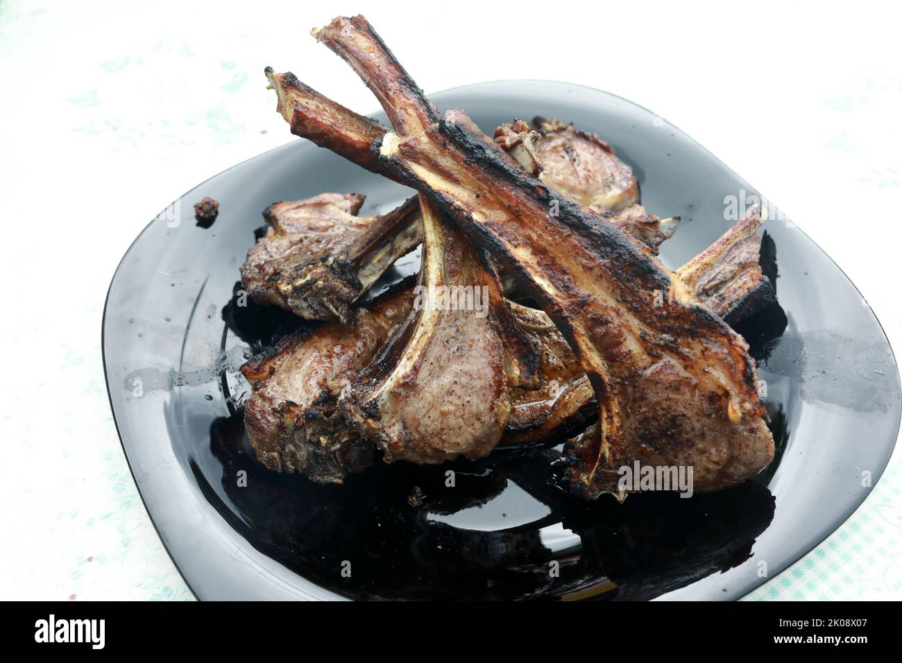 Assiette noire avec filet d'agneau grillé sur la table Banque D'Images
