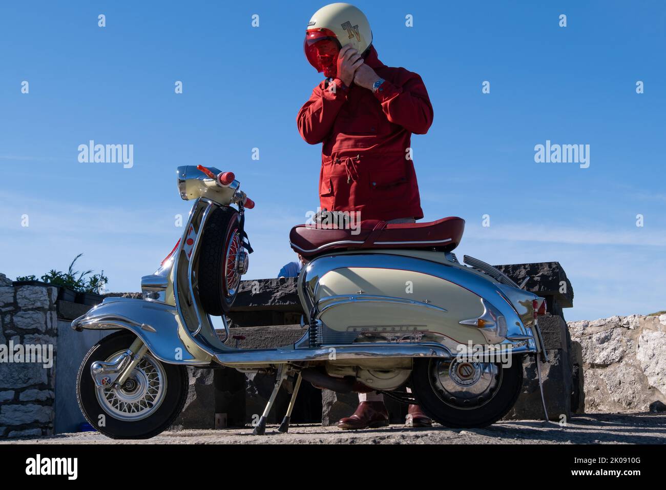 Homme en veste rouge sur le point de monter Lambretta TV 175 vintage scooter italien lors du rassemblement du rassemblement des Clans. Ballintoy, Royaume-Uni - 10 septembre 2022. Banque D'Images