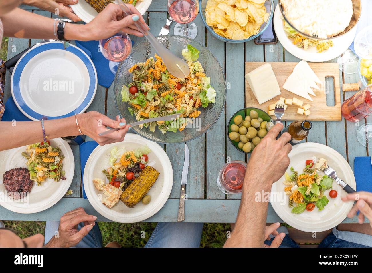 Photo créative de vos amis assis sur une table en bois. Amis qui dînaient. Ils ont des assiettes pleines de nourriture et des verres avec des boissons. Banque D'Images