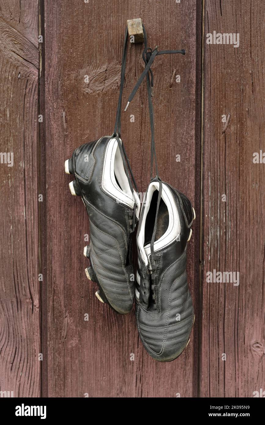 Une paire de chaussures de football accrochées à un mur en bois. La fin de la carrière de football Banque D'Images