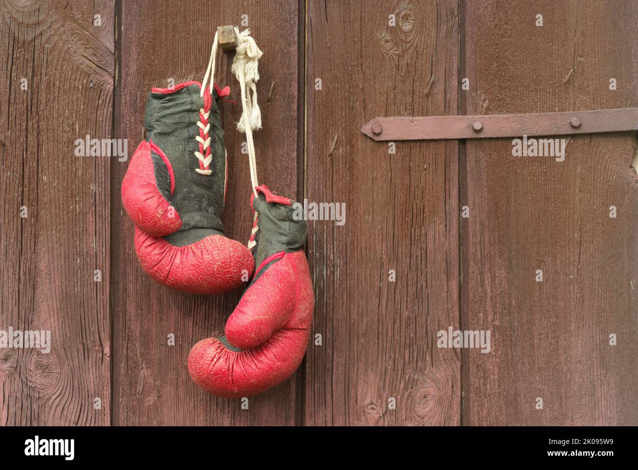 Vieux gants de boxe rouge en cuir pendent sur le fond du bois en marron Banque D'Images