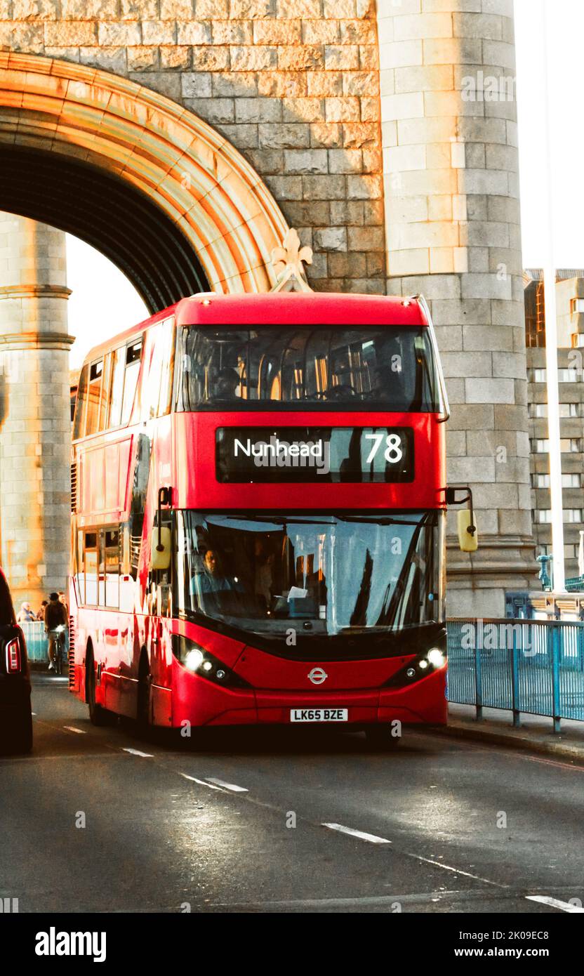 Un bus de Londres qui traverse un itinéraire traverse le Tower Bridge de Londres et est entièrement en service en soirée en été. Banque D'Images