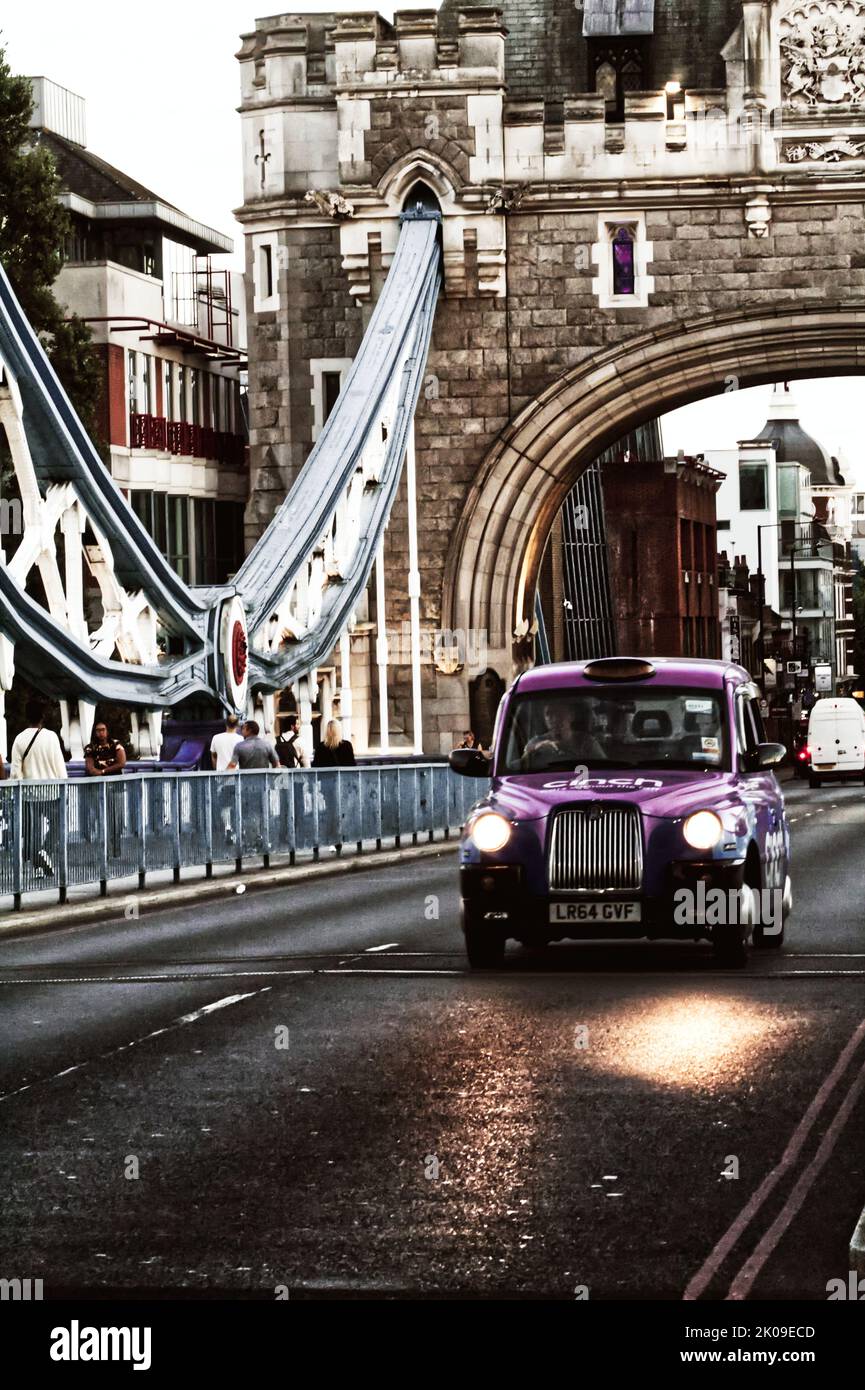 Un taxi londonien traverse le pont de la tour lors d'une soirée d'été ensoleillée dans le centre de Londres. La voiture transporte des passagers dans tout Londres. Banque D'Images