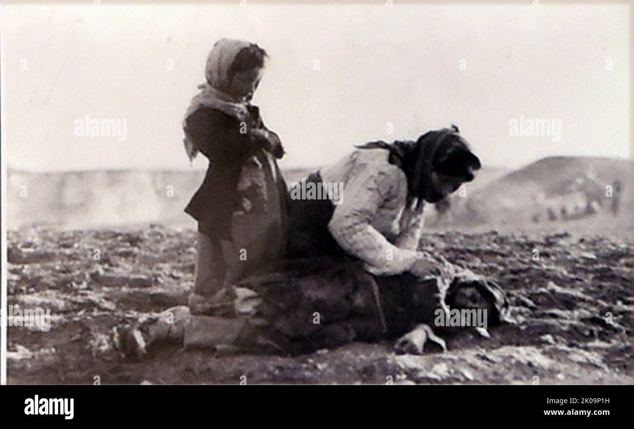 Une arménienne s'agenouillant à côté d'un enfant mort dans un champ à l'extérieur d'Alep. Génocide arménien. Le génocide arménien a été la destruction systématique du peuple et de l'identité arméniennes dans l'Empire ottoman pendant la première Guerre mondiale. Mené par le Comité d'Union et de progrès au pouvoir (CUP), Elle a été mise en œuvre principalement par le meurtre en masse d'environ un million d'Arméniens lors des marches de la mort dans le désert syrien et par l'islamisation forcée des femmes et des enfants arméniens. Banque D'Images