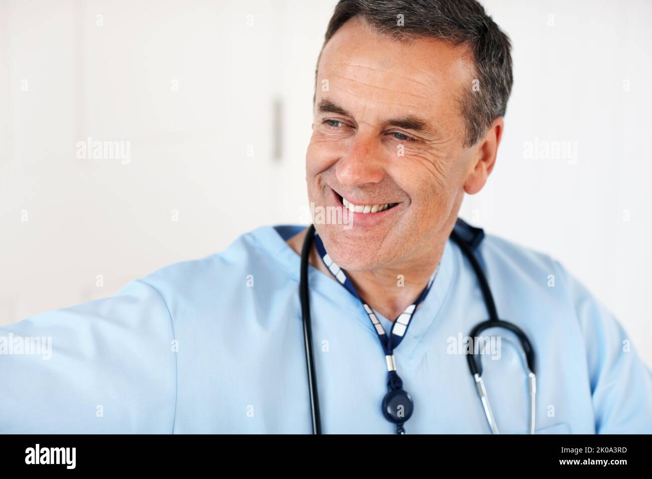 Un médecin expérimenté et mature souriant contre le blanc. Gros plan portrait d'un médecin expérimenté et mature souriant contre le blanc. Banque D'Images