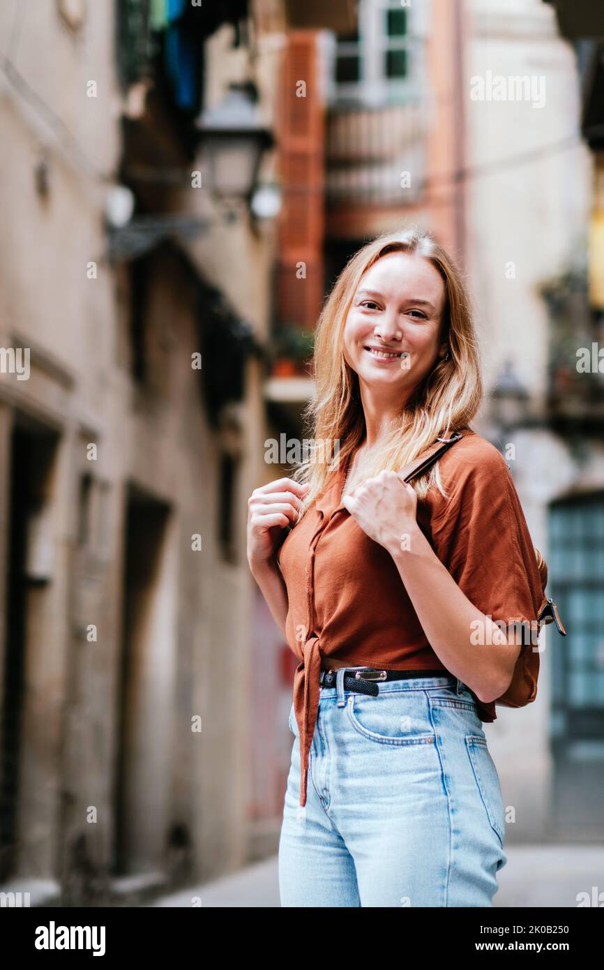 Une jeune femme blonde partage son bonheur lors d'une visite de la vieille ville de Barcelone. Elle regarde l'appareil photo et sourit Banque D'Images