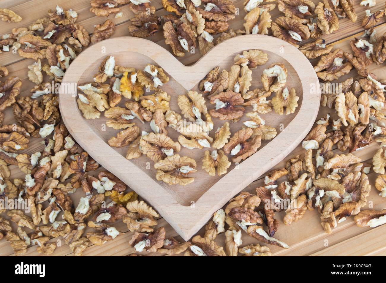 Noyaux de noyer dans une plaque en forme de coeur en bois gros plan - avantages du concept de wanlnuts Banque D'Images