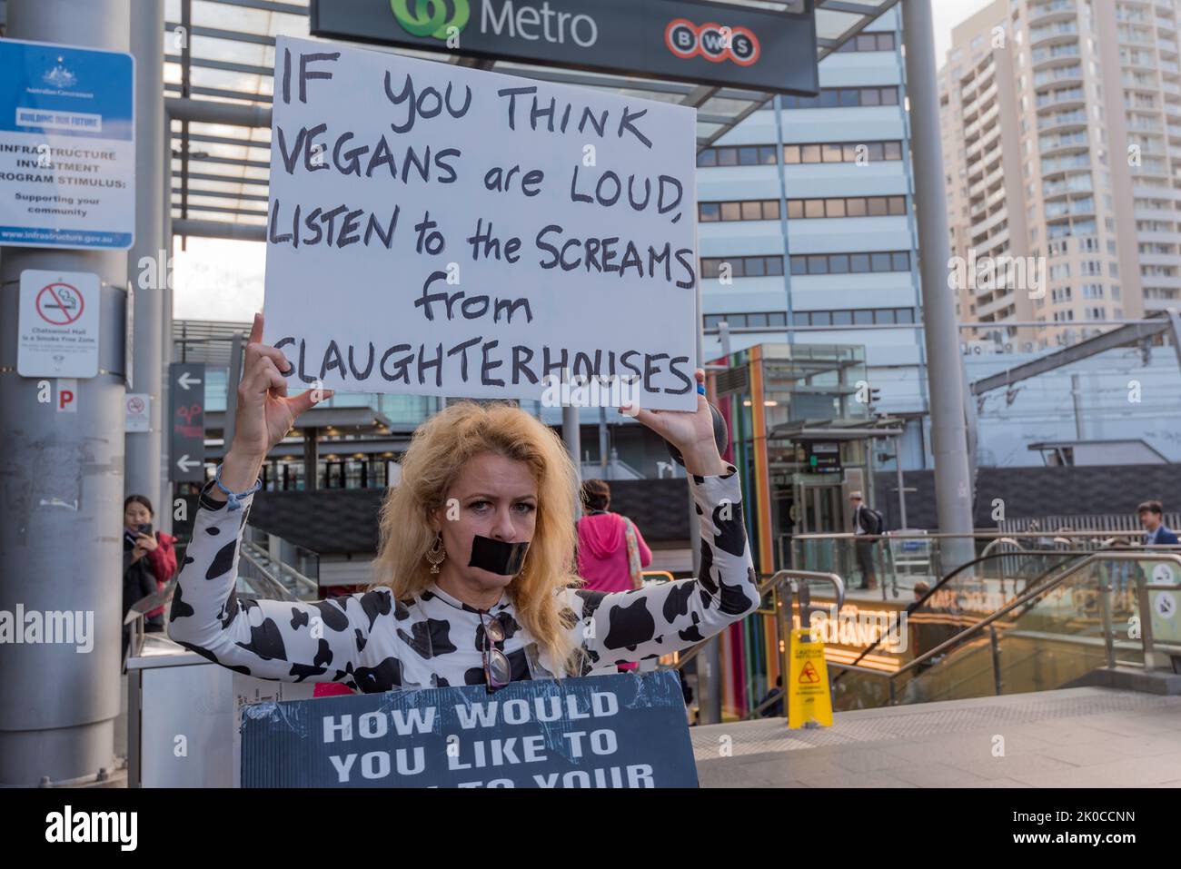 Une femme solitaire vegan manifestant portant un panneau sandwich et tenant un écriteau avec sa bouche collée. La police a demandé à l'activiste de continuer Banque D'Images