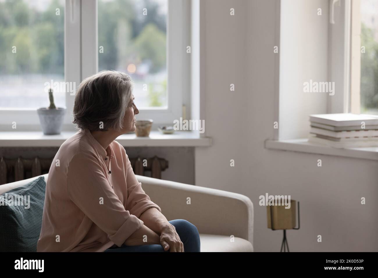 Femme solitaire attentionnés à la retraite assise sur un canapé à la maison Banque D'Images